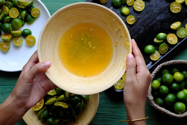 La gente tiene in mano il succo di kumquat che spremuto dalla frutta — Foto Stock