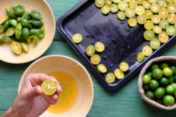 Människor hand pressa saft ur kumquat frukter halveras i — Stockfoto