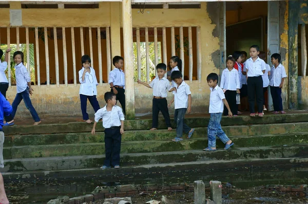 Long Viet Nam 2013年11月11日 ベトナムの小さな男の子の生徒のグループは制服を着ています 白いTシャツ 青いズボンは貧しい建物の前の浸水した学校の庭で一緒に楽しみながら立っています — ストック写真