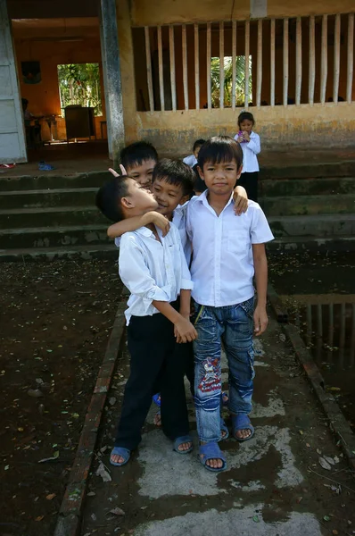 Long Viet Nam 2013年11月11日 ベトナムの小さな男の子の生徒のグループは制服を着ています 白いTシャツ 青いズボンは貧しい建物の前の浸水した学校の庭で一緒に楽しみながら立っています — ストック写真