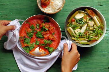 Öğle yemeğinde Vietnam yemeği, ev yapımı vejetaryen yemeği, domates soslu tofu topu aşçısı, bambu filizli sebze çorbası, su ıspanağı, pirinç kasesi, yeşil ahşap zeminde vejetaryen yemeği.