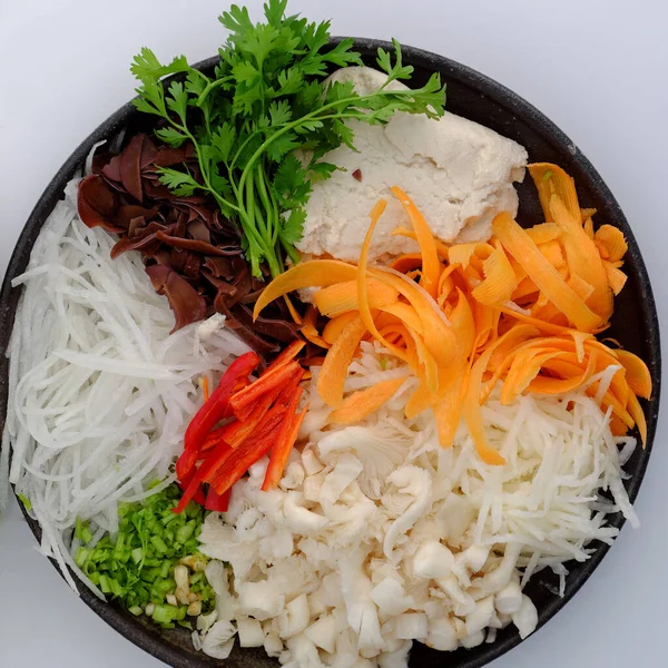 Top view raw material for flat rice dumpling from vegetable as carrot, mushroom, tofu, radish, yam bean with rice flour and leaf to package, homemade food, vegan rice cake leaf, a special cake of Hue