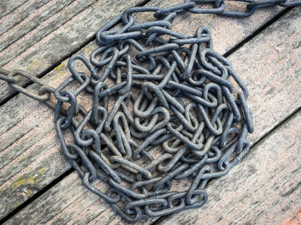 Metal chains - abstract  background. Ships anchor chain lying on the wooden floor. Heap of old ship anchor chain links close-up. Grunge Vintage Style Background.