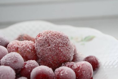 Beyaz bir tabakta donmuş kiraz ve çilek.