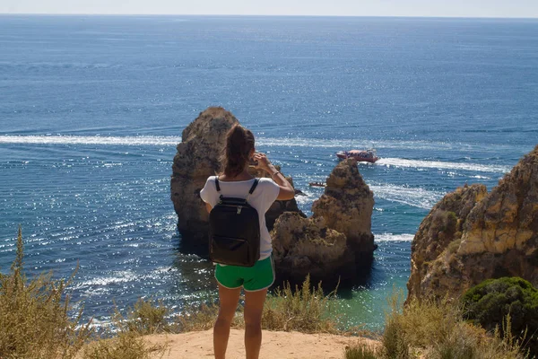Genç kadın Algarve kıyısında kayalar ve okyanus bir fotoğraf çekmek
