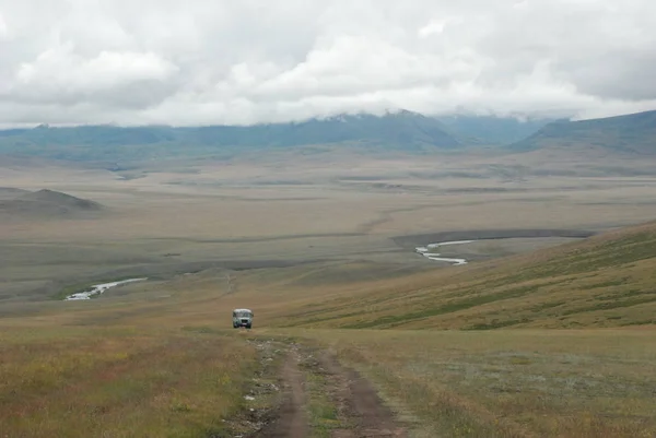 Orta Asya. Mongun uzak alanda - Taiginsky kozhuun, Tuva Cumhuriyeti, bir yolcu otobüsü vardır. Aşağıda Mogen-Buren nehri vadisi ve bulutların çok ötesinde gizli dağlar vardır.