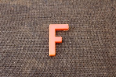 Ahşap arkaplanda çok renkli plastik alfabe harfi izole edildi