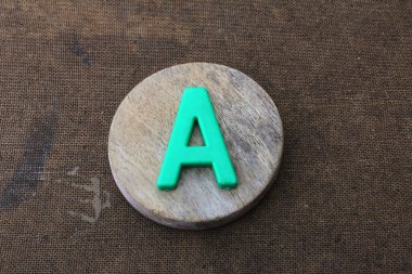 Ahşap arkaplanda çok renkli plastik alfabe harfi izole edildi