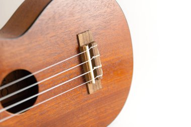Koyu kahverengi ukulele Hawaii gitarının yakın plan görüntüsü seçilmiş odak noktası ve beyaz arkaplanda izole edilmiş kopyalama alanı.