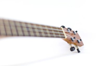 Koyu kahverengi ukulele Hawaii gitarının yakın plan başı seçilmiş odak noktası ve beyaz arkaplanda izole edilmiş kopyalama alanı.