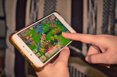 Cep telefonu ekranında parmak, bir tarım mobil oyunu oynuyor