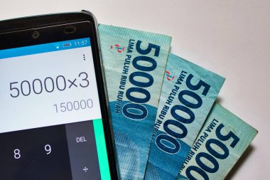 Endonezya rupiah faturaları ve kalkütör uygulaması çalıştıran bir cep telefonu