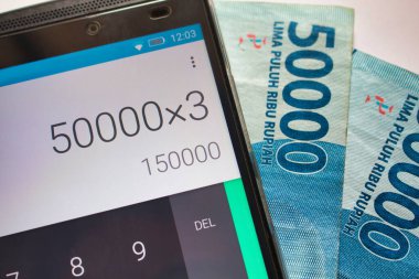 Endonezya rupiah faturaları ve kalkütör uygulaması çalıştıran bir cep telefonu