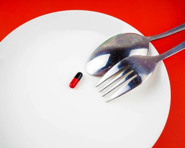 Çatal ve kaşık beyaz plaka üzerinde tıbbi ilaçlar