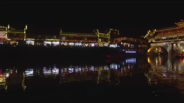 Fenghuang éjszakai kilátás nyílik a folyóparton. Az emberek sétálnak az utcán, a vásárlás és érezd jól magad. Fények tükröződik a folyón teszi a szép lövés, Hunan tartomány, Kína.