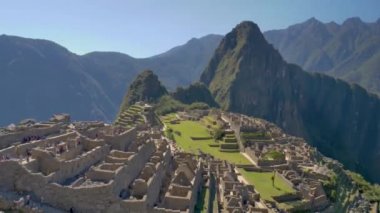 Machu Picchu 'nun arkeolojik kompleksinin arka planında Huayna Picchu dağı var. Öğleden sonra birkaç turistle. Cusco Bölgesi, Peru