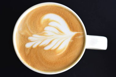 Koyu ahşap masada latte sanatının üst görünümü.   