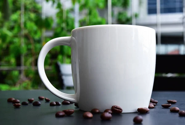 Cap de café en la mesa de madera oscura tienen muchos granos de café . — Foto de Stock