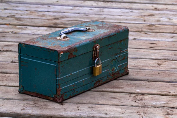 Rusty old toolbox locked up sitting on a wood