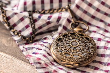 Ekose bir bezin üstünde oturan cep saati. Cep saatinde saat 03:49.