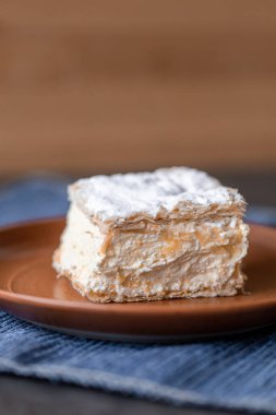 Bir tabağın üstünde otururken kremnit. Genellikle üzerine krema serpiştirilmiş ve üzerine serpiştirilmiş üç katmanlı fileto pastasından yapılır..