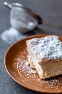 Bir tabağın üstünde otururken kremnit. Genellikle üzerine krema serpiştirilmiş ve üzerine serpiştirilmiş üç katmanlı fileto pastasından yapılır..