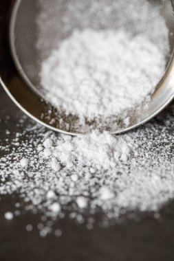 Bir masanın üstünde oturan ağ süzgecindeki pudra şekerini kapat