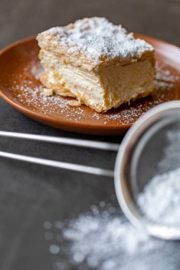 Bir tabağın üstünde otururken kremnit. Genellikle üzerine krema serpiştirilmiş ve üzerine serpiştirilmiş üç katmanlı fileto pastasından yapılır..