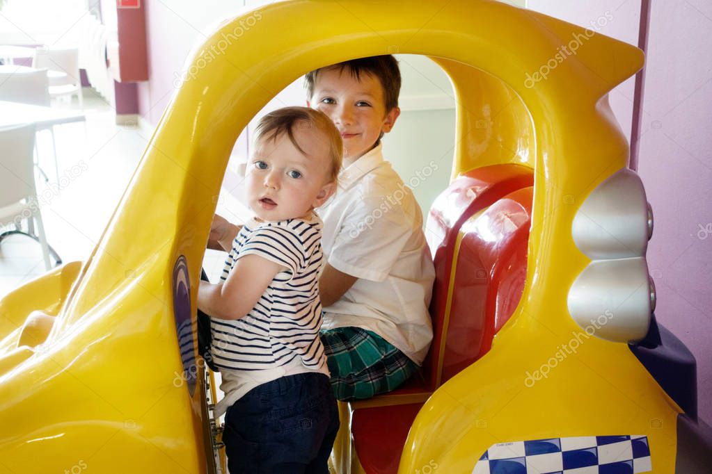 Two little boys sitting in amusement park ride