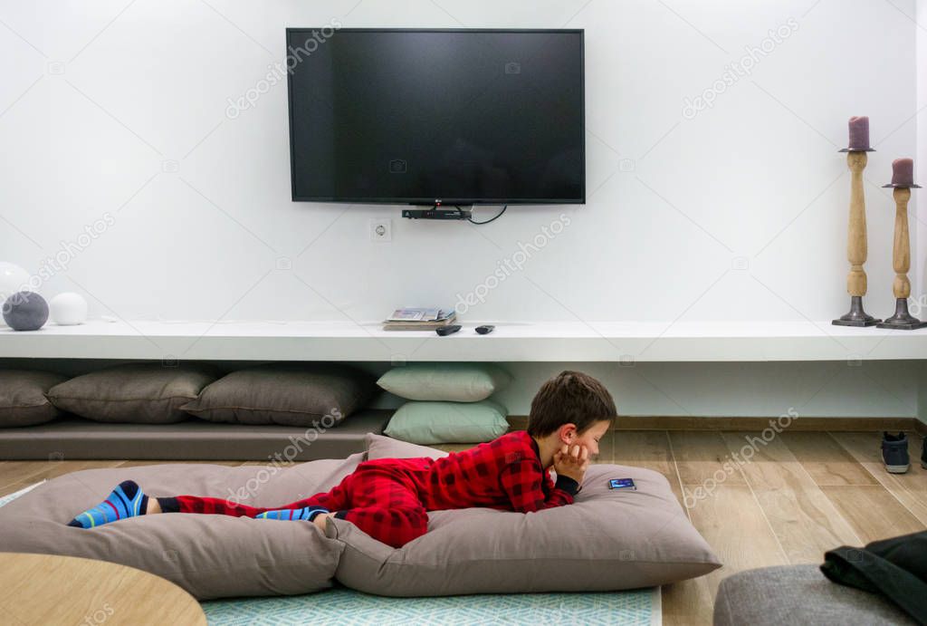 Boy watching on mobile while lying down on sofa at Crete, Greece, Europe