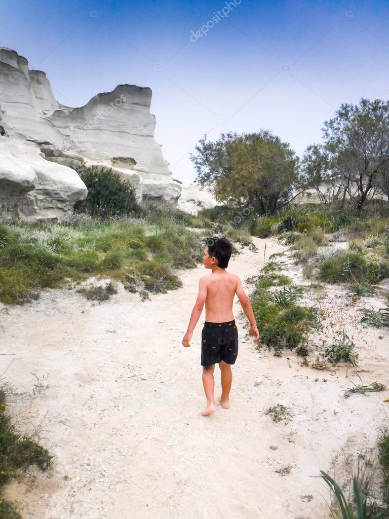 Boy walking on sand at Milos island, Greece