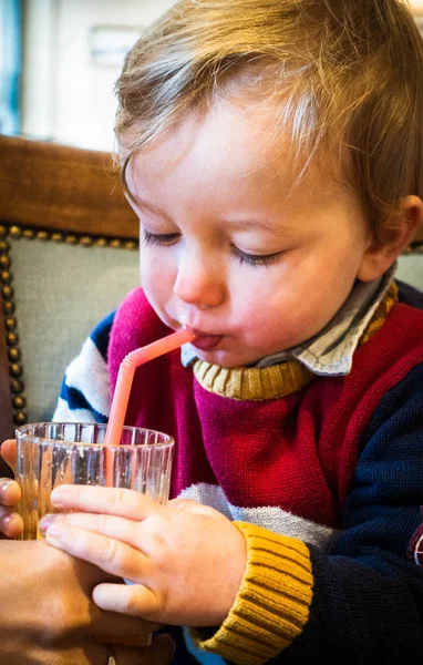 Pojke dricker från glas genom halm — Stockfoto