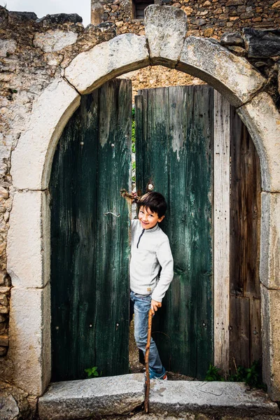 Lachende jongen gluren door houten deur — Stockfoto