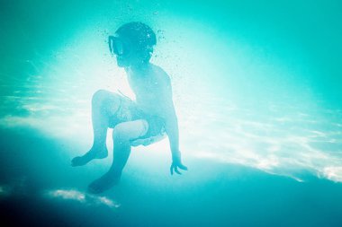 Çocuk suyun altında yüzüyor.