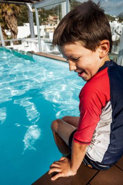 Havuz kenarında oturan çocuk