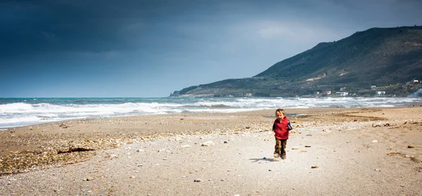 Menino alegre andando na praia — Fotografia de Stock