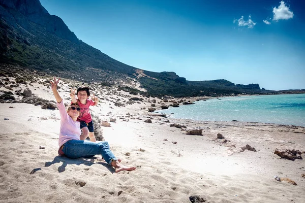 Moeder met zoon gebaren v, teken op het strand — Stockfoto