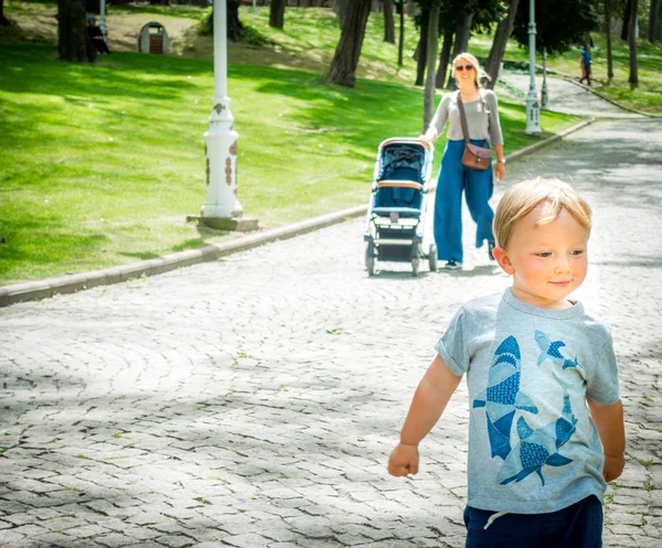 Matka pozoruje svého chlapečka, jak hraje v parku — Stock fotografie