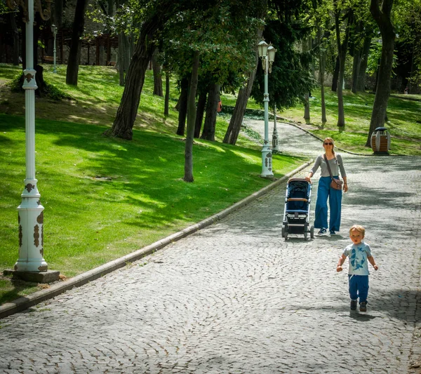 公園で遊んでいる彼女の赤ちゃんの男の子を見ている母 — ストック写真