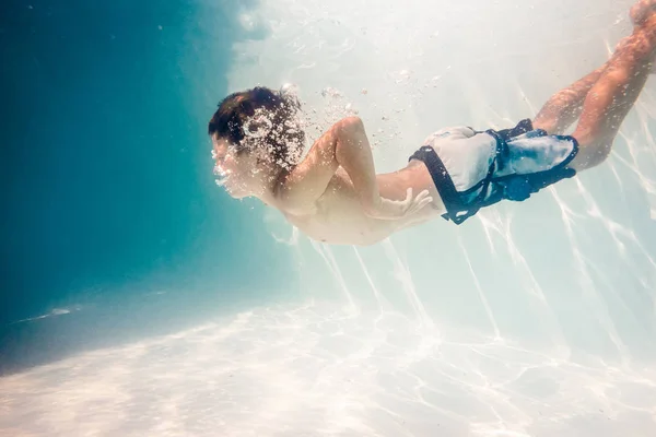Pojke simmar under vatten — Stockfoto