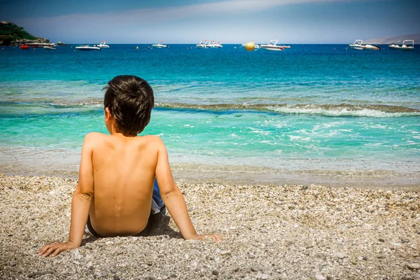 Chłopiec siedzi na piasku na plaży — Zdjęcie stockowe