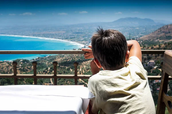 Мальчик созерцает через балкон отеля глядя на остров на — стоковое фото