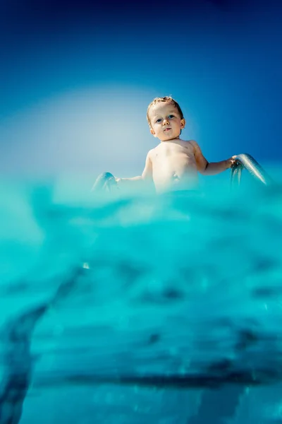 Baby pojke stående på stege av pool — Stockfoto