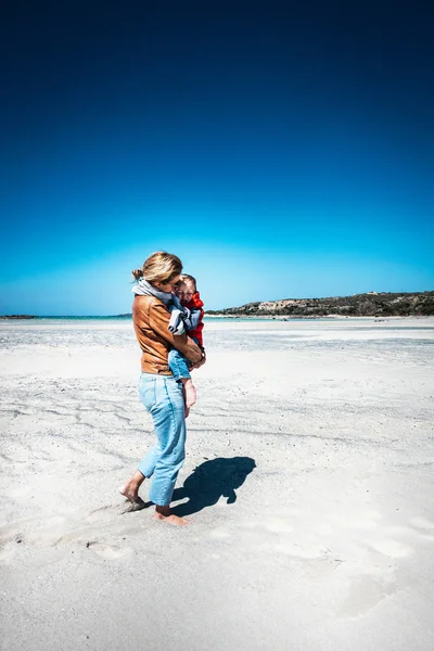 Moeder draagt zoon op het strand — Stockfoto