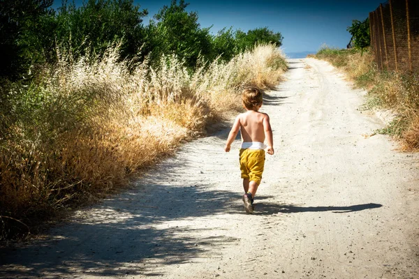Visão traseira de uma criança correndo em direção à praia. Grécia — Fotografia de Stock