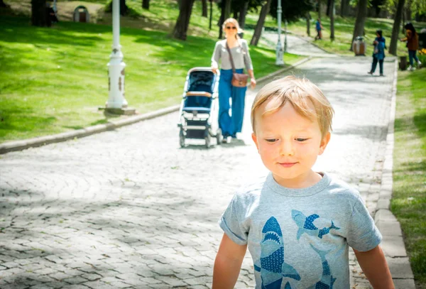 Matka pozoruje svého chlapečka, jak hraje v parku — Stock fotografie