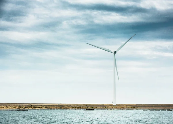 Wind turbine on agriculture field by sea — Stock Photo, Image