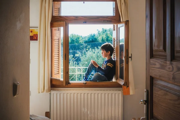 Boy sitting on window sill — Stock Photo, Image