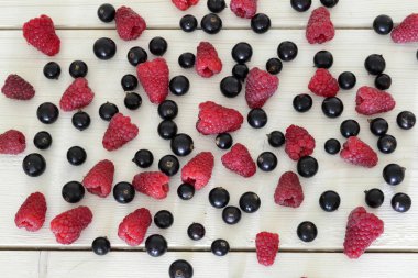 ahşap masa üzerinde ahududu ve siyah frenk üzümü