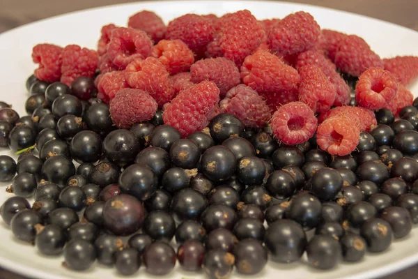 Arándanos y frambuesas en un plato sobre una mesa de madera — Foto de Stock